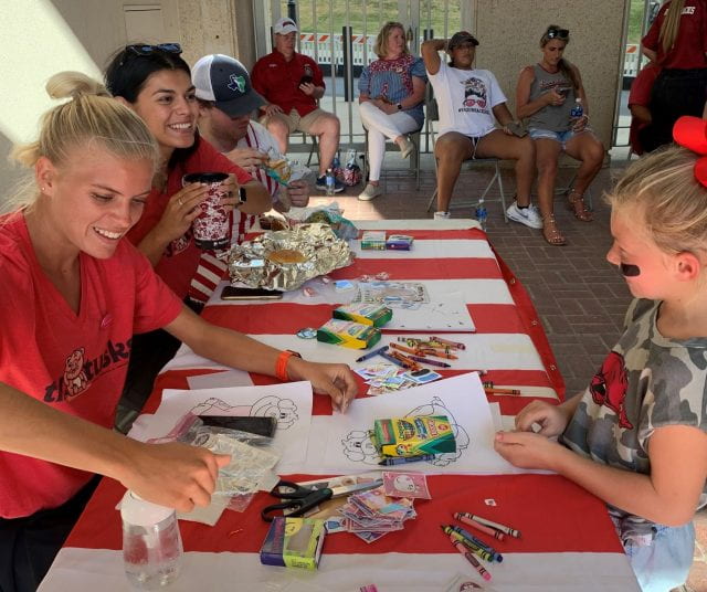 University of Arkansas nursing student and track athlete Quinn Owen works with a child at the Tiny Tusks booth.