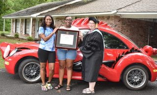 Tiffany Trotter, center, with her daughter, Raina, receives a framed diploma from Patty Milner of the U of A Global Campus during a presentation Aug. 4 on the RazorBug Diploma Tour through eastern Arkansas. The diploma tour celebrated graduates who earned U of A degrees online without leaving their hometowns, jobs and families.